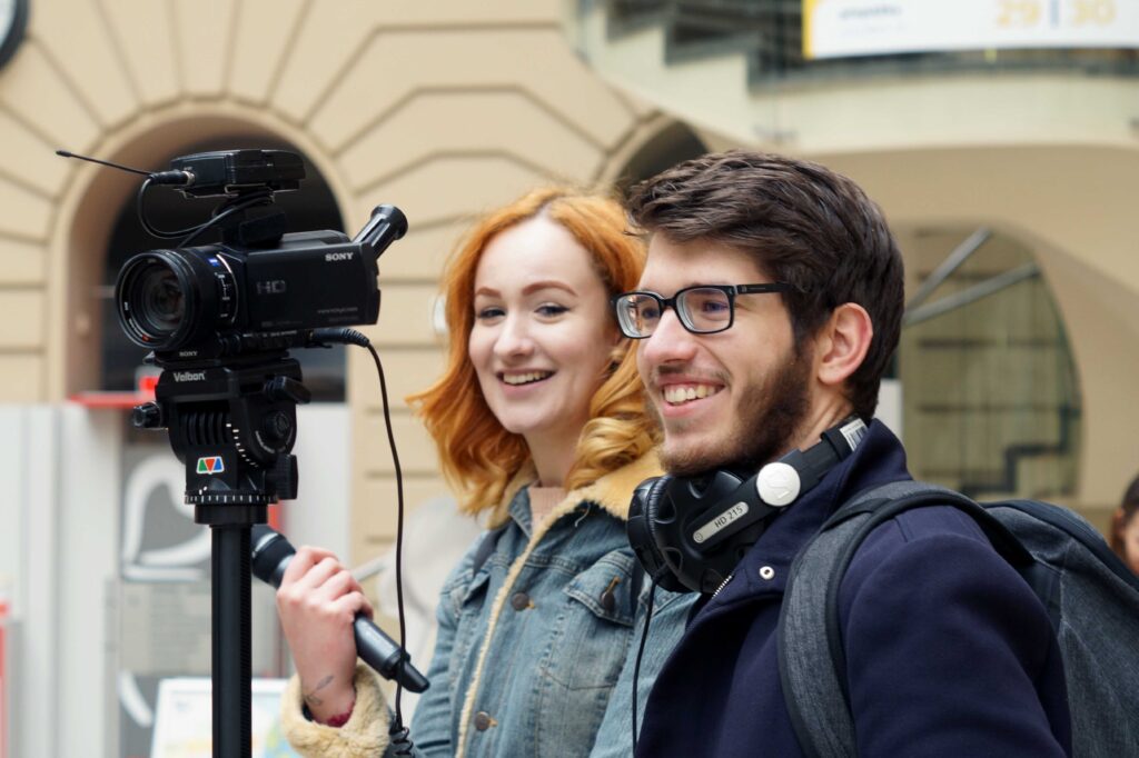 mladí studenti publicistiky, kluk adívka s kamerou a sluchátkami